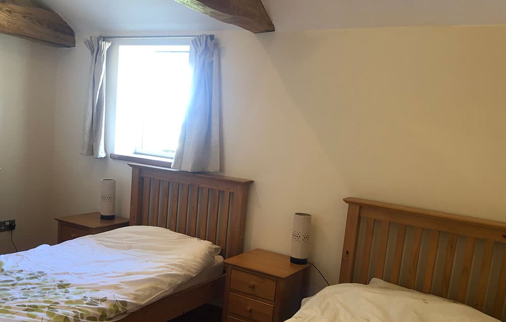 Twin bedroom with two pine single beds and bedside tables under a beamed ceiling