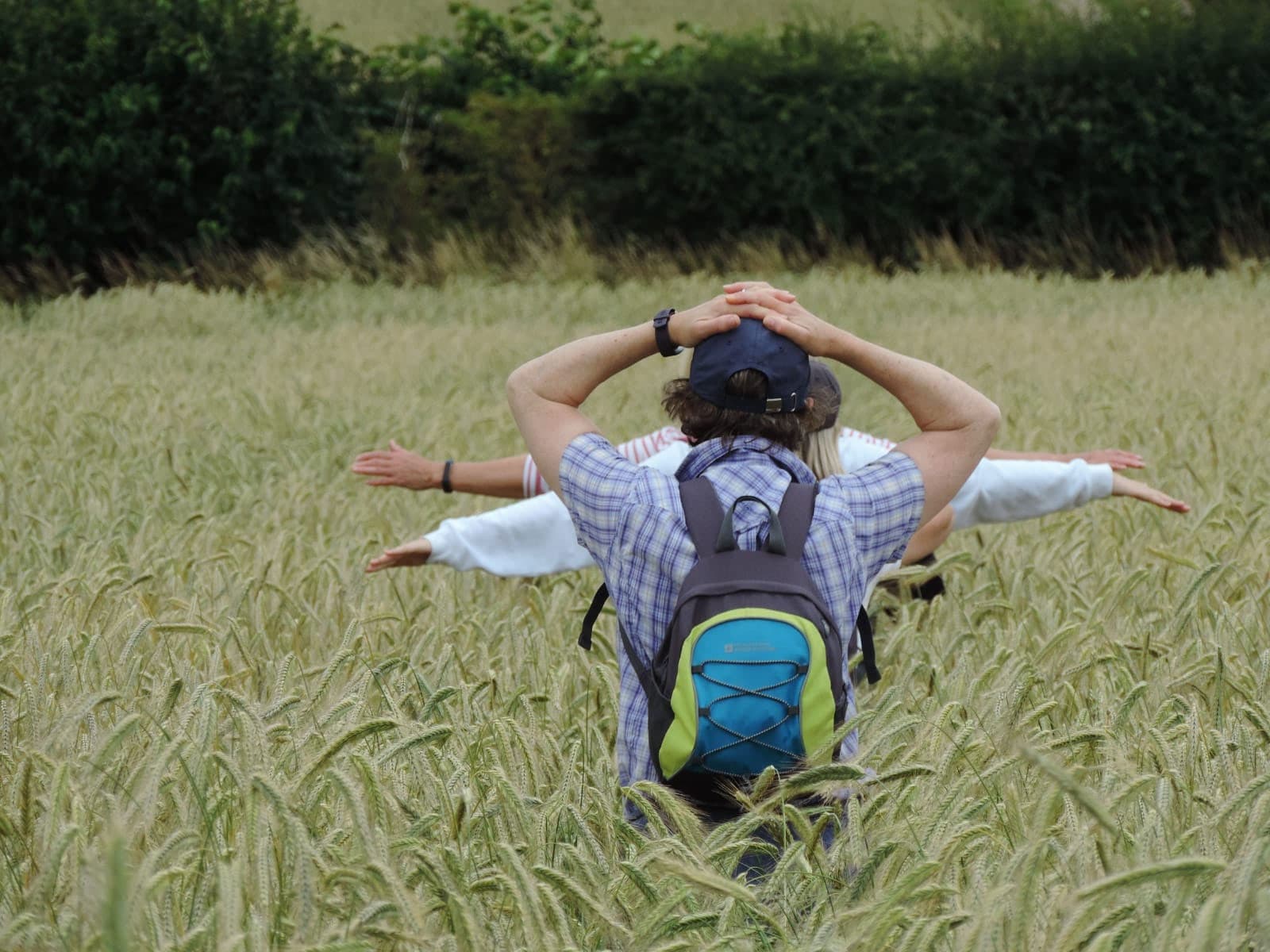 Two people walking through a field of tall wheat, one with arms outstretched