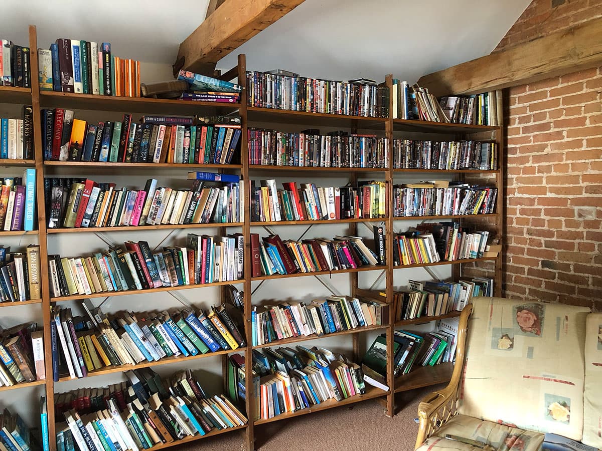 Floor-to-ceiling shelves of books beside an exposed brick wall, with an armchair