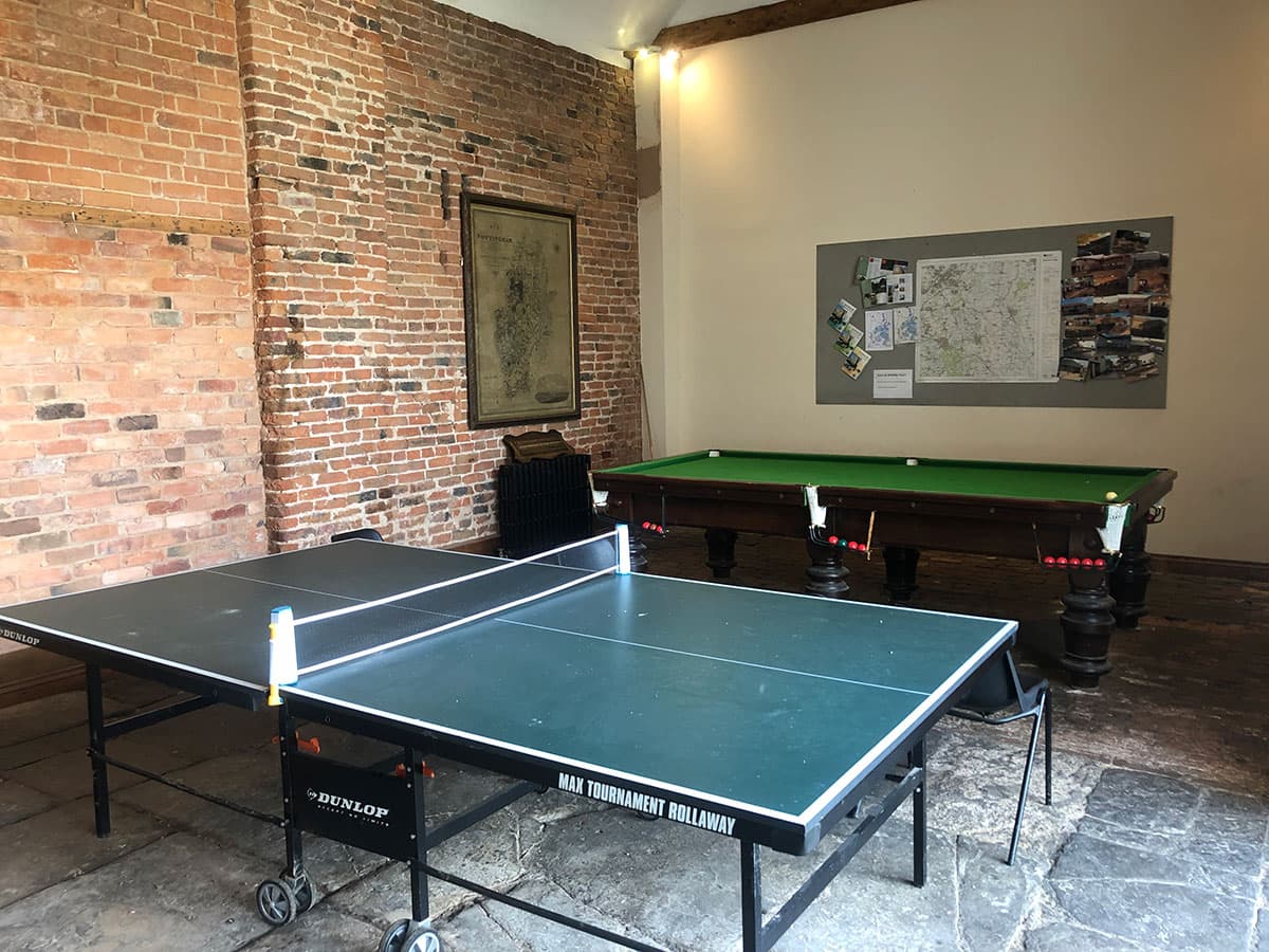 Games room with a table tennis table and a snooker table in front of an exposed brick wall
