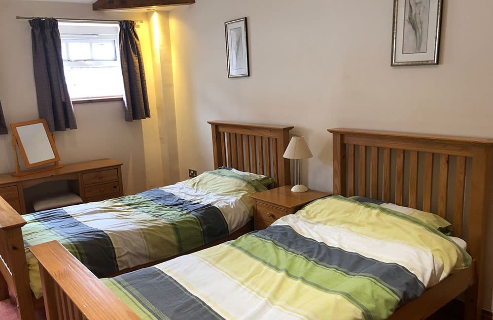 Twin bedroom with two pine single beds with green and grey striped covers
