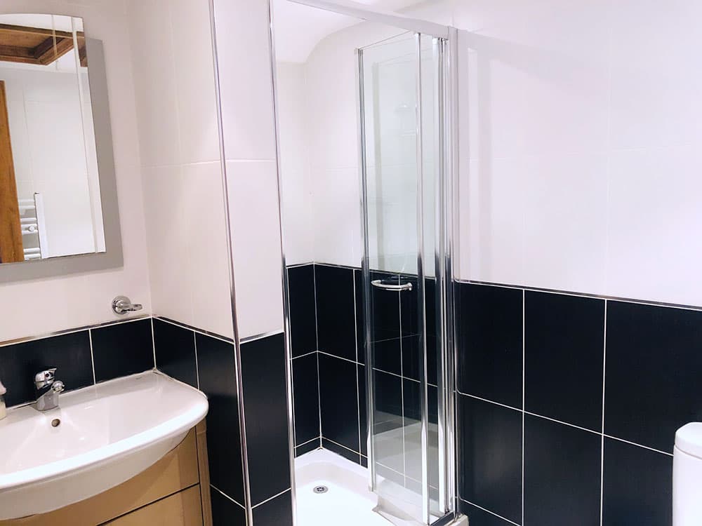 Shower room with a glass shower enclosure, black and white tiles and a vanity basin