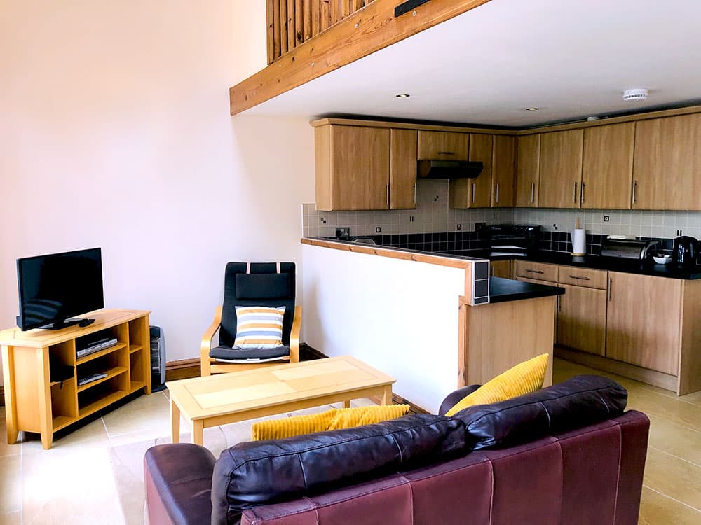 Open-plan living room and kitchen beneath a mezzanine balcony