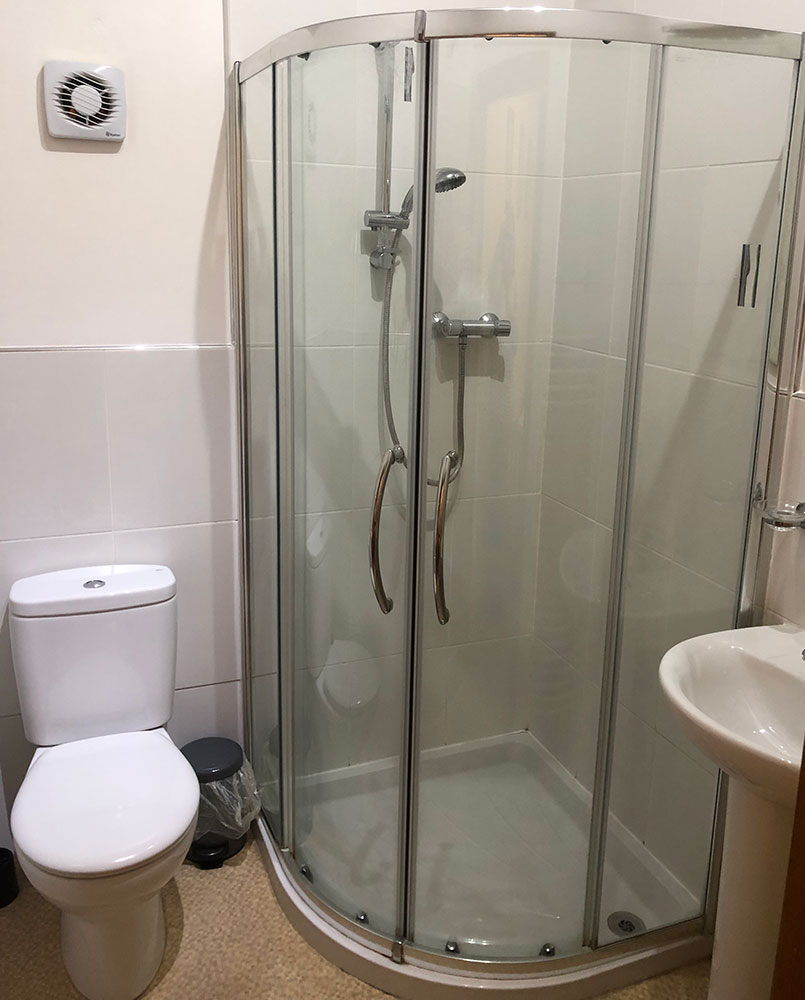 Shower room with a curved glass shower cubicle, toilet and basin