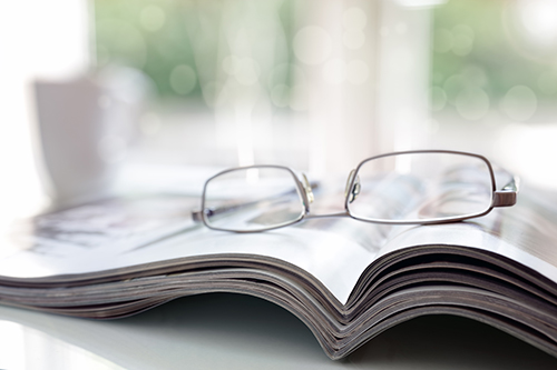 Reading glasses resting on an open magazine